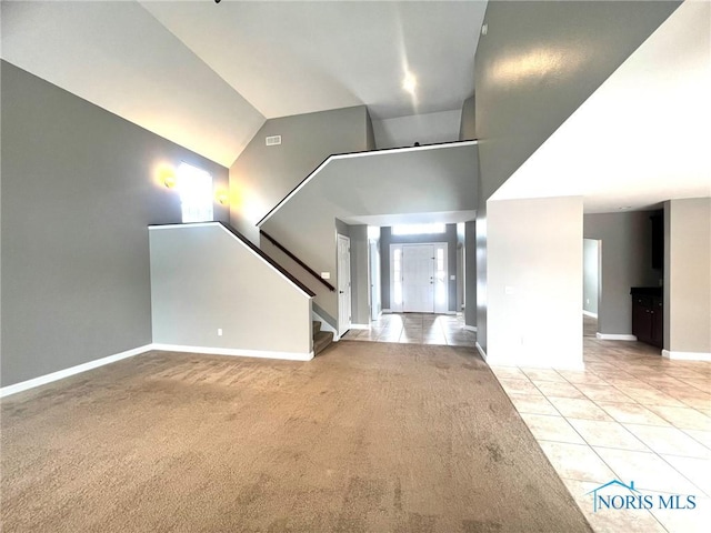 unfurnished living room featuring light carpet and high vaulted ceiling