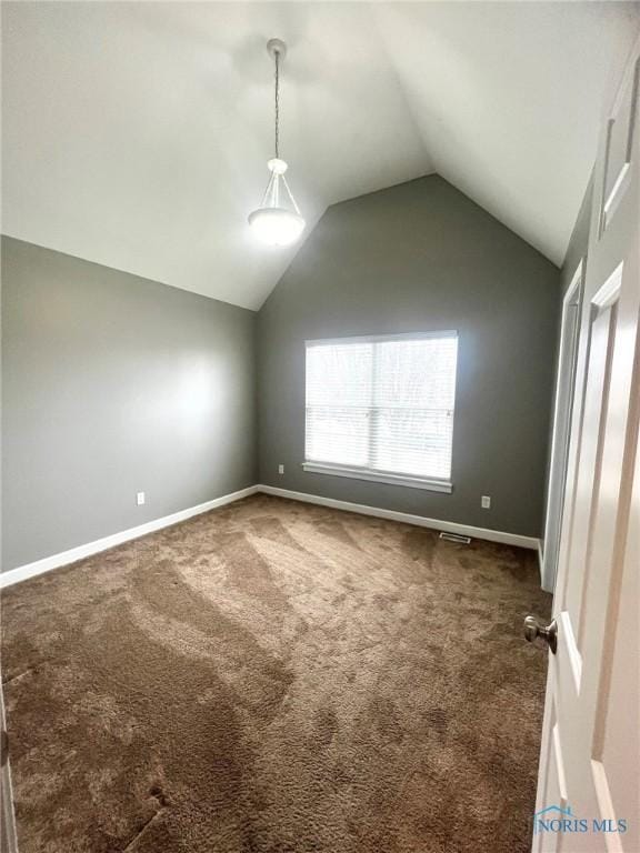 spare room featuring lofted ceiling and dark colored carpet