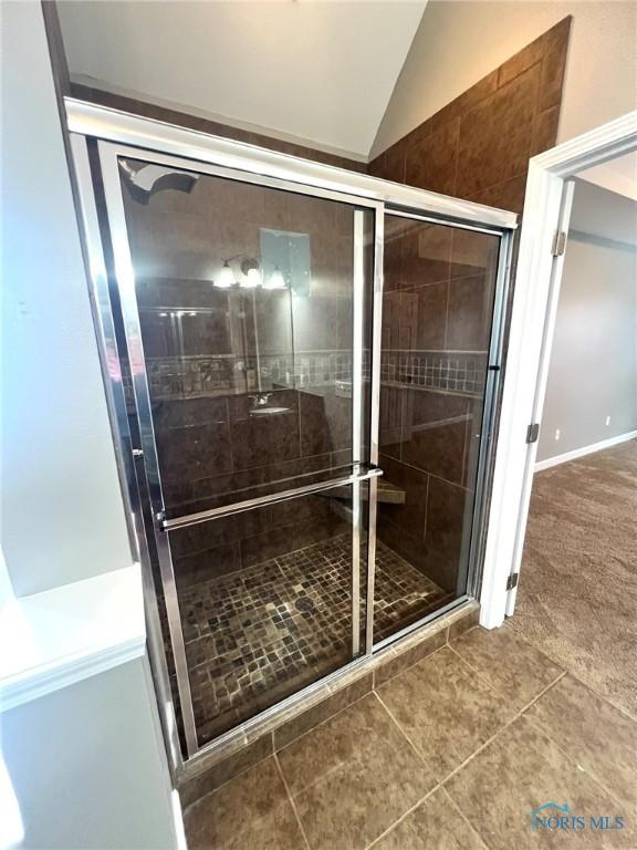 bathroom featuring lofted ceiling, an enclosed shower, and tile patterned flooring