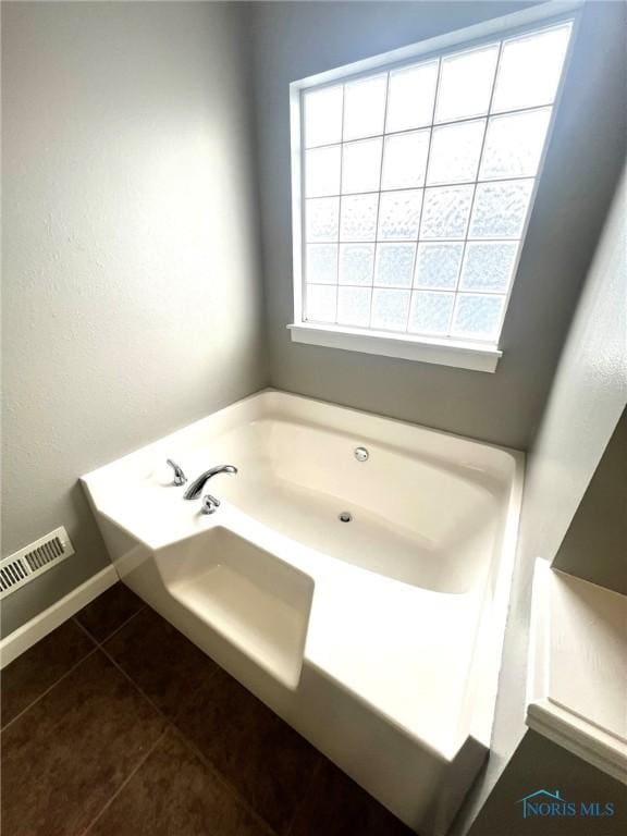 bathroom featuring tile patterned flooring, a wealth of natural light, and a bathing tub