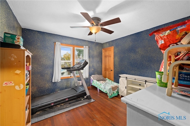 workout room featuring hardwood / wood-style floors, ceiling fan, and a textured ceiling