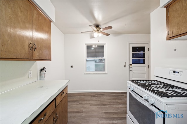 kitchen featuring white gas range, ceiling fan, and dark wood-type flooring