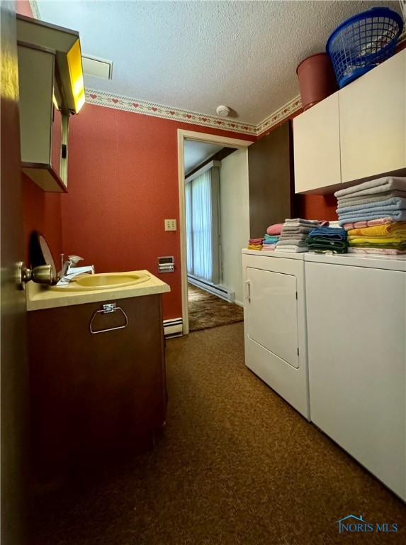 laundry area featuring dark carpet, cabinets, sink, and washing machine and clothes dryer