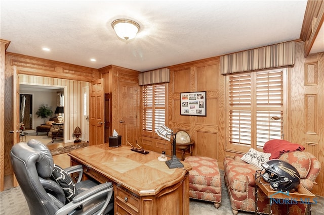 carpeted office space with wood walls and a textured ceiling