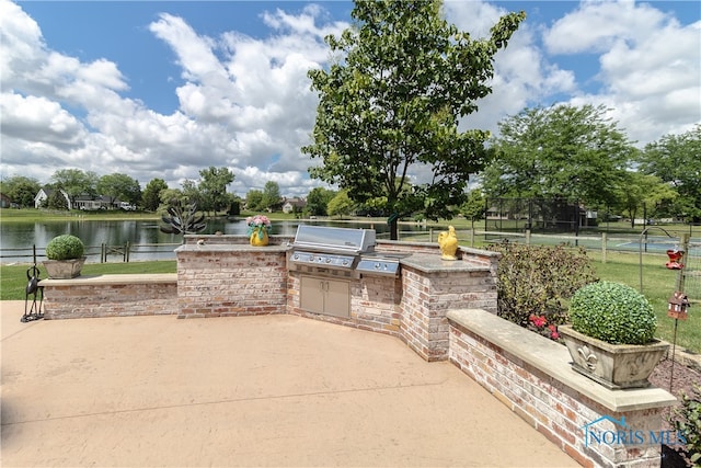 view of patio featuring tennis court, a water view, area for grilling, and exterior kitchen