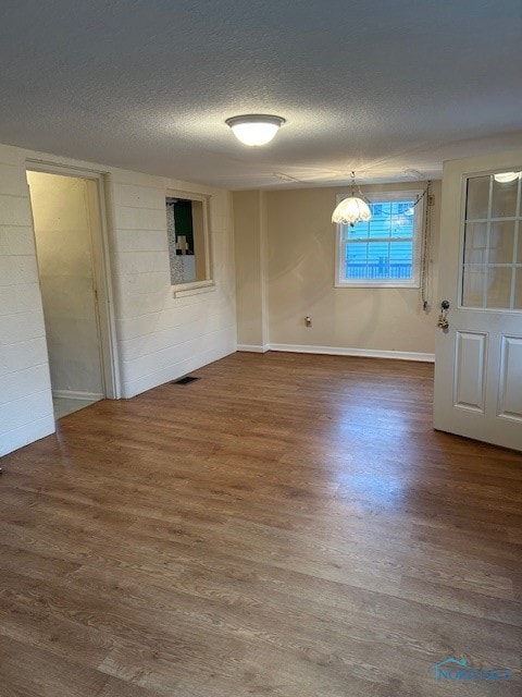 unfurnished room featuring dark hardwood / wood-style floors, a textured ceiling, and a chandelier