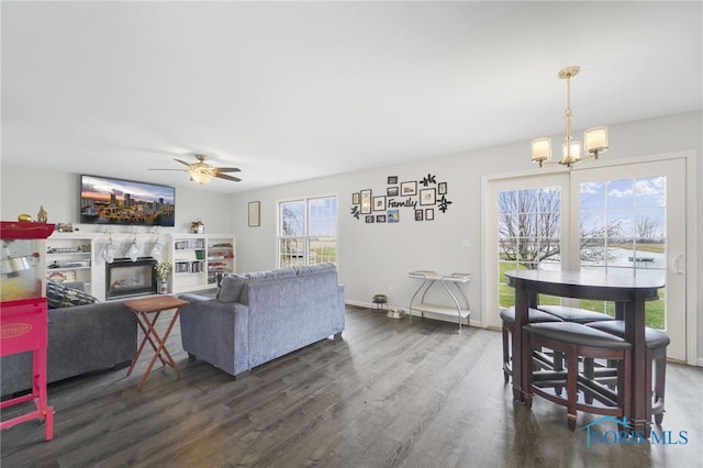 living room with dark wood-type flooring and ceiling fan with notable chandelier