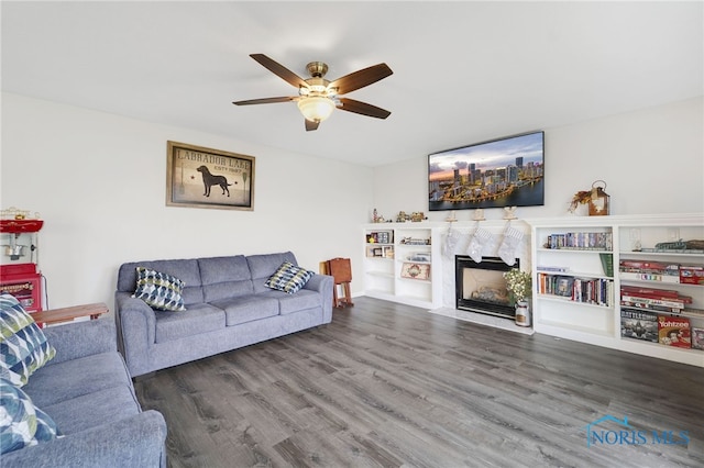 living room with ceiling fan, a fireplace, and dark wood-type flooring