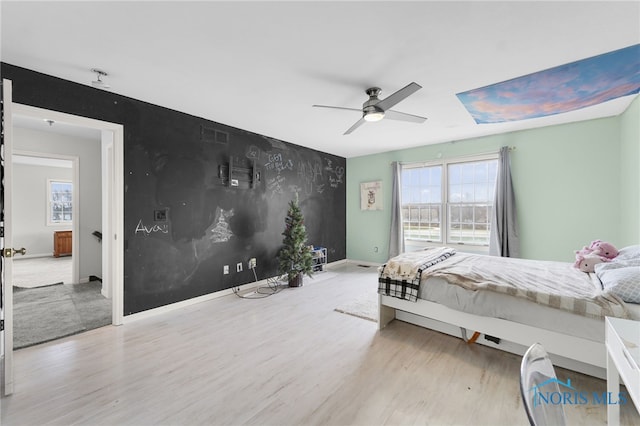 bedroom with multiple windows, light hardwood / wood-style floors, and ceiling fan