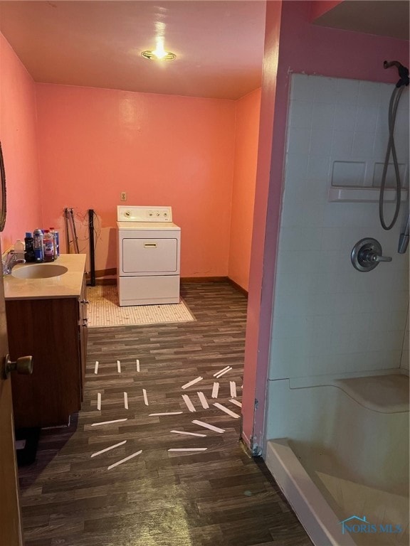 bathroom with walk in shower, hardwood / wood-style floors, vanity, and washer / dryer