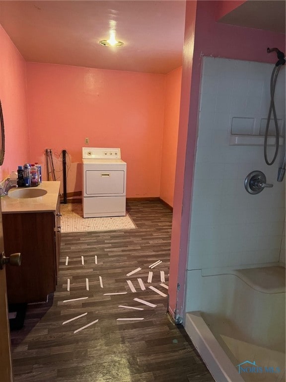 bathroom featuring hardwood / wood-style flooring, vanity, washer / dryer, and walk in shower