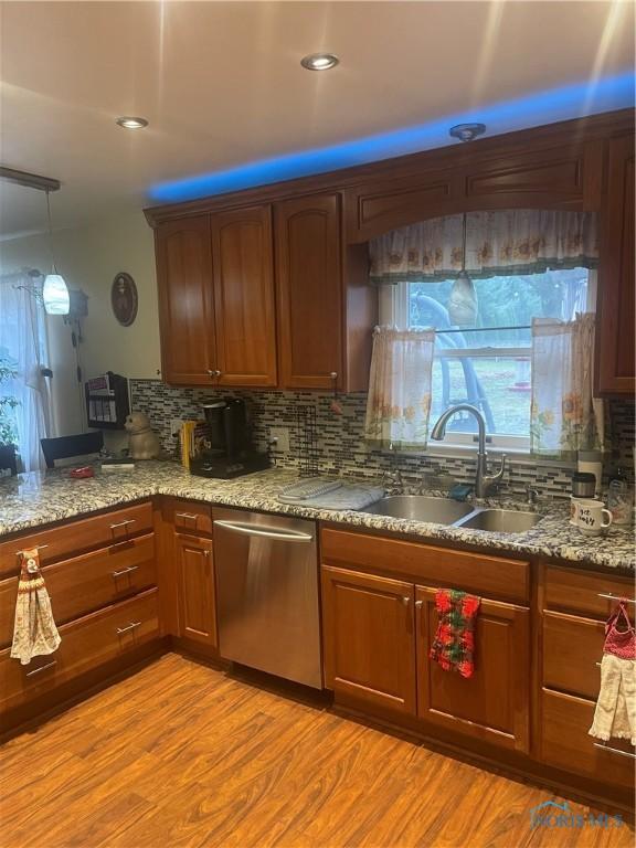 kitchen with tasteful backsplash, sink, stainless steel dishwasher, and light hardwood / wood-style floors