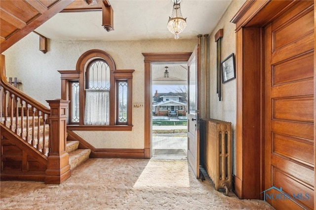 carpeted entrance foyer with a notable chandelier