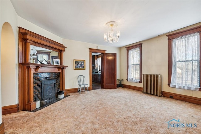 unfurnished living room featuring carpet, radiator, and an inviting chandelier