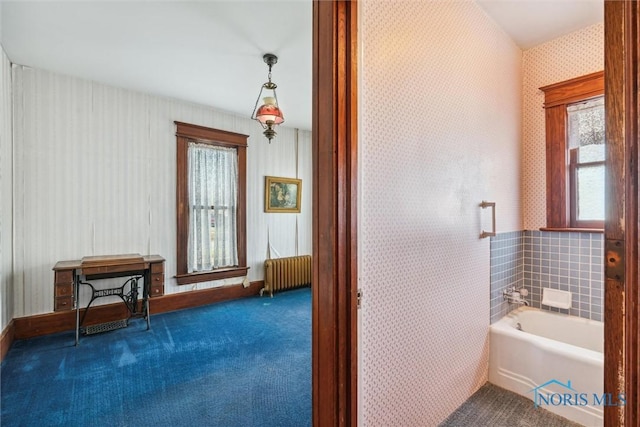 bathroom featuring a tub to relax in, radiator, and tile walls