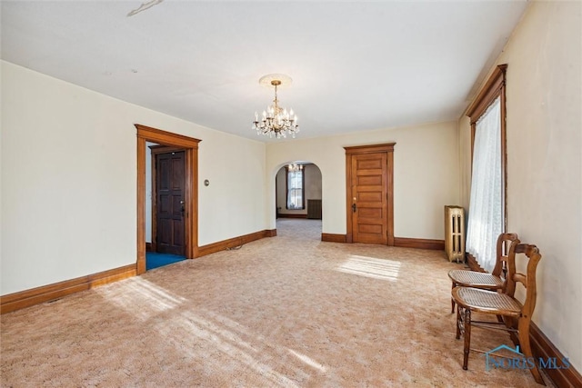 carpeted spare room with a notable chandelier and radiator