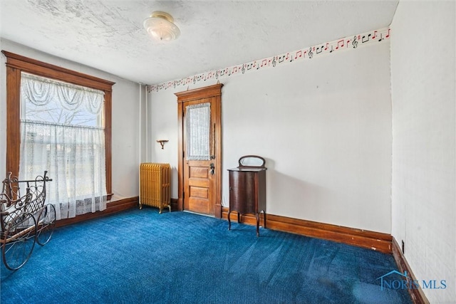 carpeted empty room with radiator heating unit and a textured ceiling