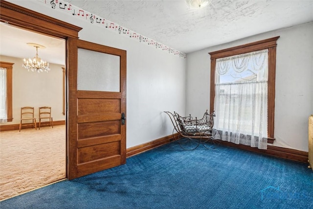 spare room featuring carpet flooring, a textured ceiling, and an inviting chandelier