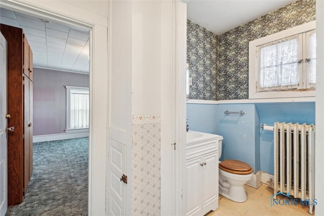 bathroom with radiator heating unit, vanity, a healthy amount of sunlight, and toilet