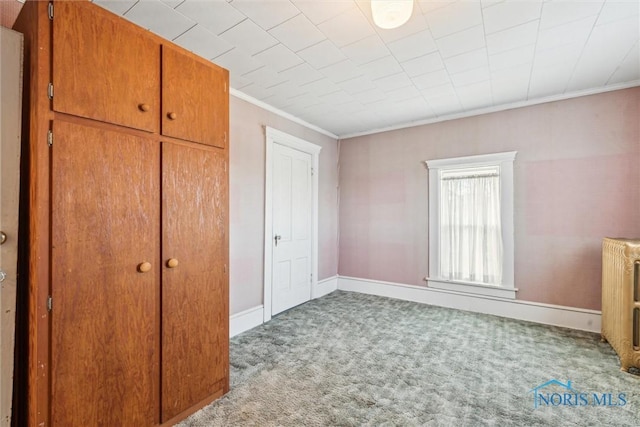 unfurnished bedroom with a closet, light carpet, radiator heating unit, and ornamental molding