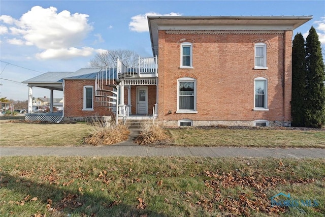 view of front facade with a balcony, central air condition unit, and a front yard