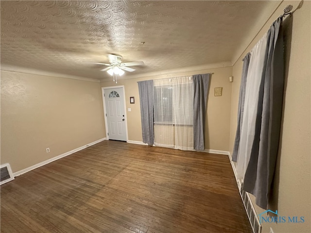 spare room featuring dark hardwood / wood-style flooring, a textured ceiling, and ceiling fan