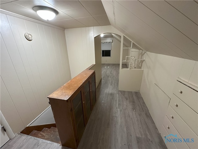 bar featuring wood-type flooring, dark brown cabinetry, and lofted ceiling