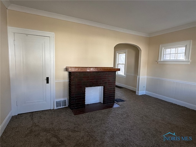 unfurnished living room with dark carpet, crown molding, and a brick fireplace