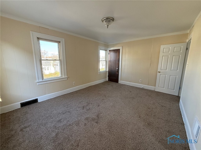 unfurnished bedroom featuring multiple windows, ornamental molding, and dark colored carpet