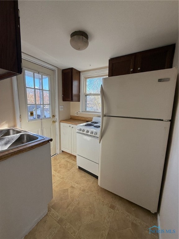 kitchen featuring dark brown cabinetry and white appliances