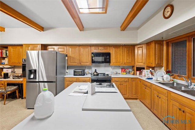 kitchen with black appliances, beam ceiling, sink, and light carpet