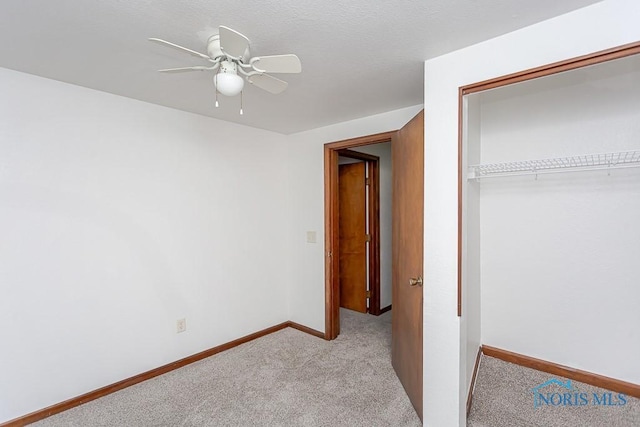 unfurnished bedroom with ceiling fan, light colored carpet, and a closet