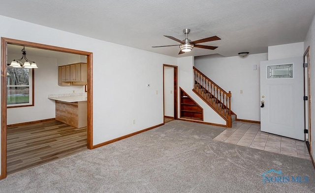 interior space featuring a textured ceiling, ceiling fan with notable chandelier, and light carpet