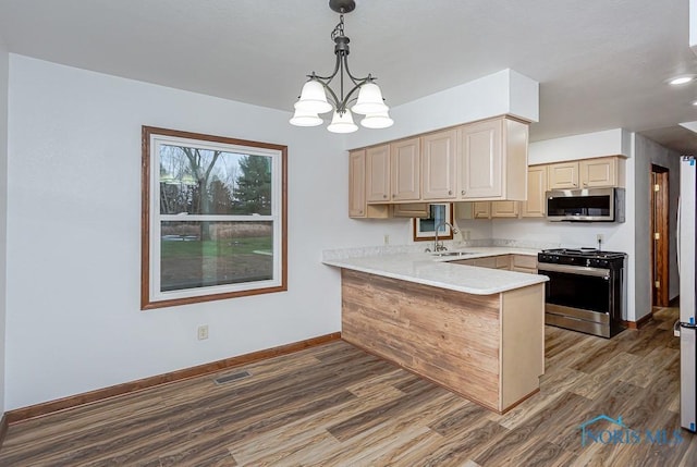 kitchen featuring sink, dark wood-type flooring, kitchen peninsula, pendant lighting, and appliances with stainless steel finishes