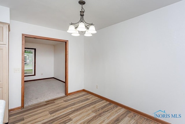 spare room featuring hardwood / wood-style floors and a chandelier