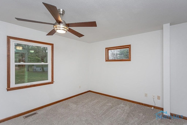 carpeted spare room with a textured ceiling and ceiling fan