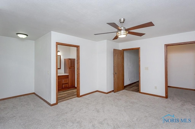 unfurnished bedroom with ceiling fan, light colored carpet, a textured ceiling, and connected bathroom