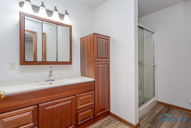 bathroom with hardwood / wood-style floors, vanity, and walk in shower