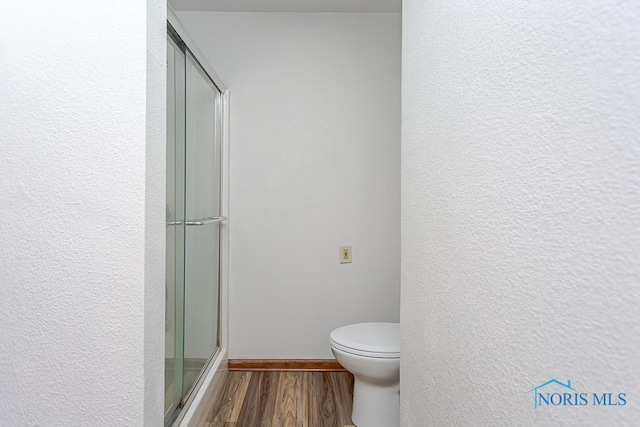 bathroom with walk in shower, toilet, and hardwood / wood-style flooring