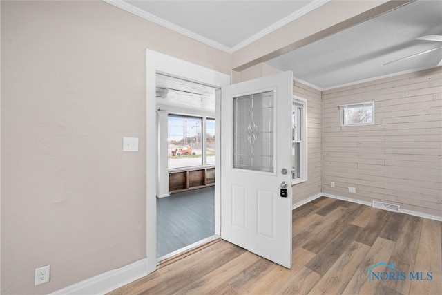 entryway with hardwood / wood-style flooring, ceiling fan, crown molding, and brick wall