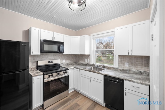 kitchen featuring backsplash, black appliances, white cabinets, sink, and light hardwood / wood-style floors