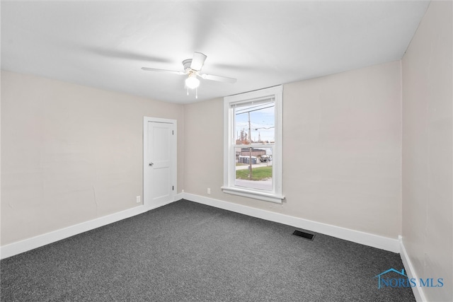 empty room with ceiling fan and dark colored carpet