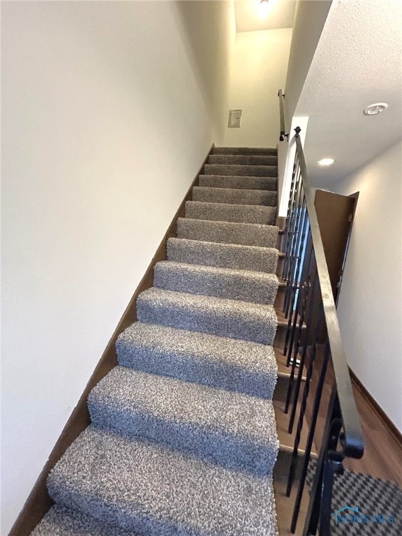 stairs featuring a textured ceiling