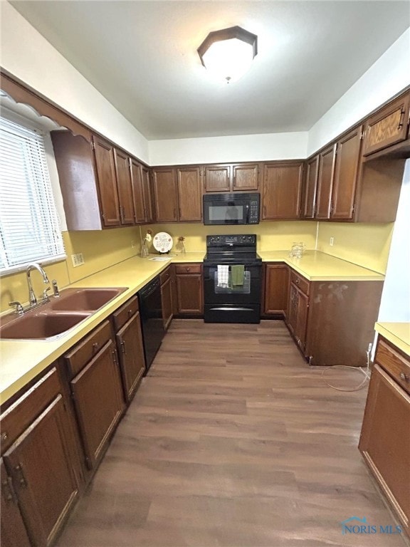 kitchen featuring dark brown cabinetry, sink, black appliances, and dark hardwood / wood-style floors