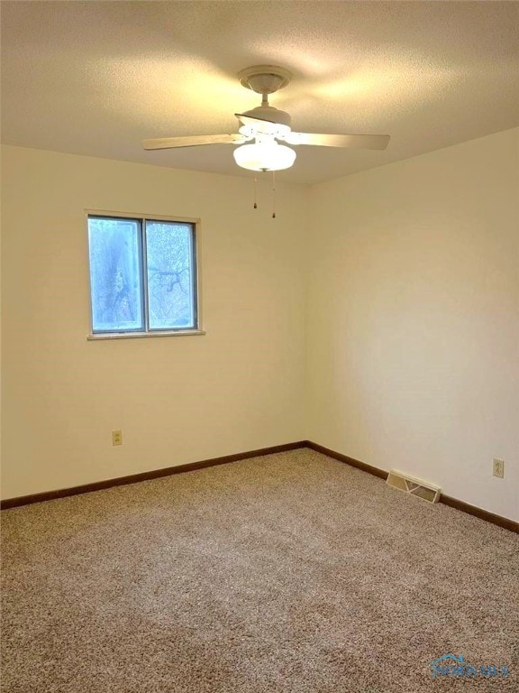 carpeted spare room with ceiling fan and a textured ceiling