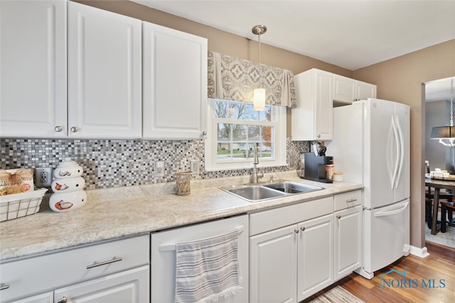 kitchen with white cabinetry, sink, hanging light fixtures, dishwashing machine, and light wood-type flooring