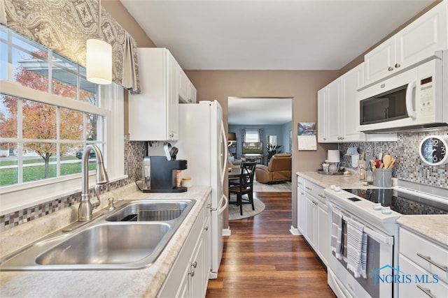 kitchen with white appliances, dark wood-type flooring, sink, decorative backsplash, and white cabinetry