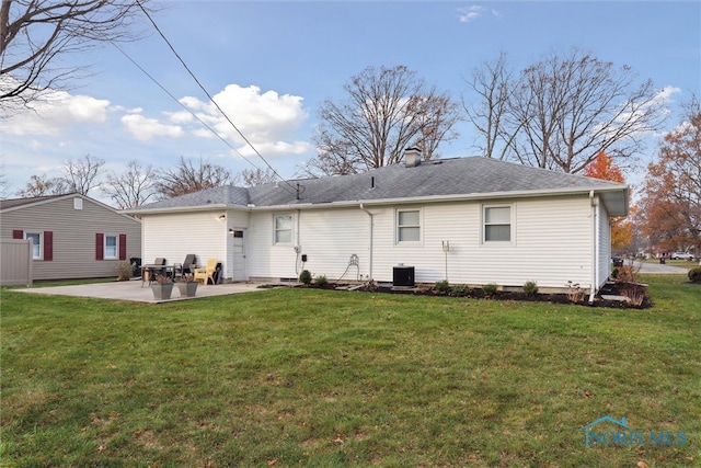 rear view of property with central AC unit, a patio area, and a yard