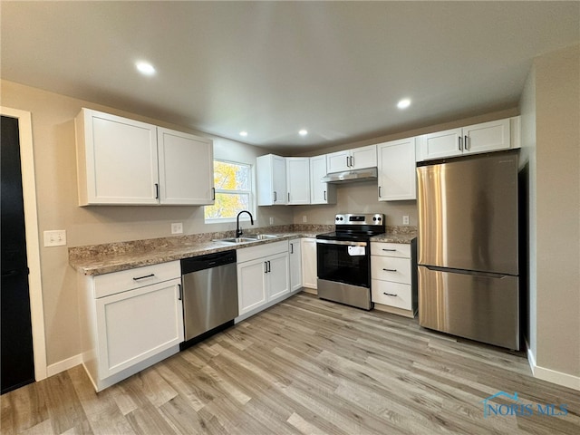 kitchen with white cabinets, sink, appliances with stainless steel finishes, light hardwood / wood-style floors, and light stone counters