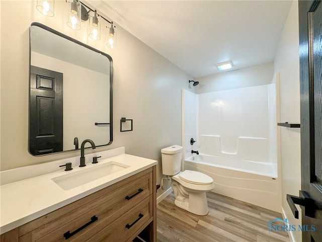 full bathroom with toilet, hardwood / wood-style floors, vanity, and washtub / shower combination